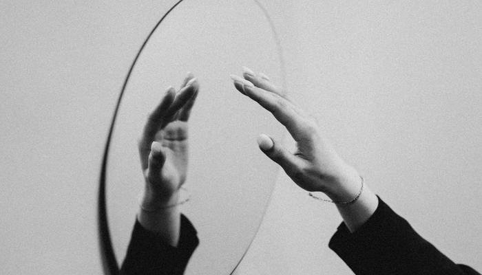 A hand touching its reflection in a mirror