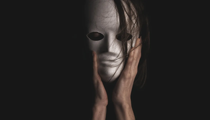 person wearing mask holding hands to face
